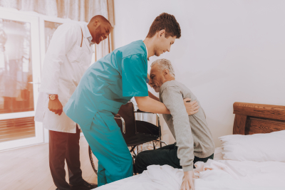 caregiver helping the old to get up from the bed