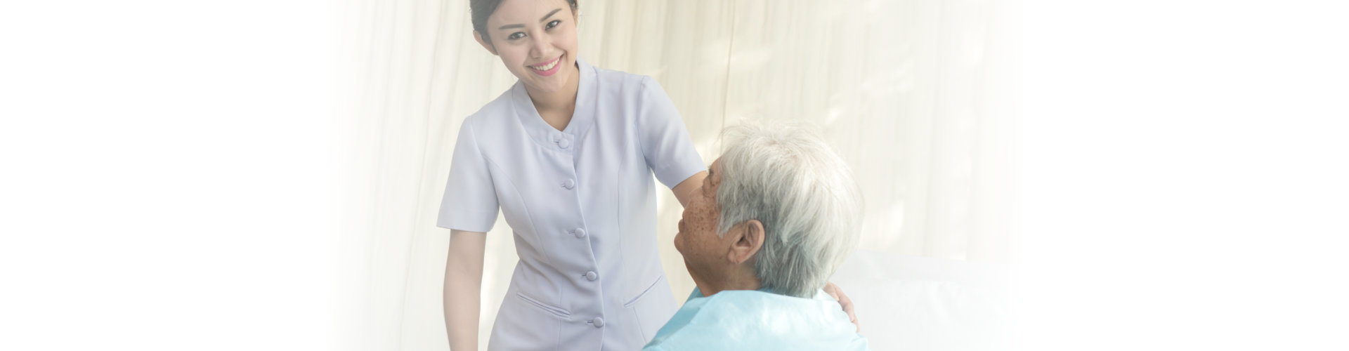 cheerful asian caregiver smiling to the camera while holding the old lady